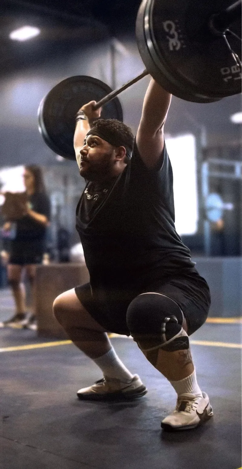 An athlete catching a heavy squat clean on the training floor