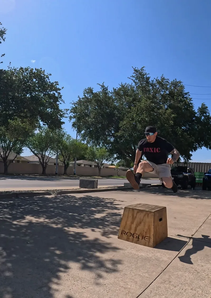 Athlete mid-air during an outdoor box jump in the Texas sun