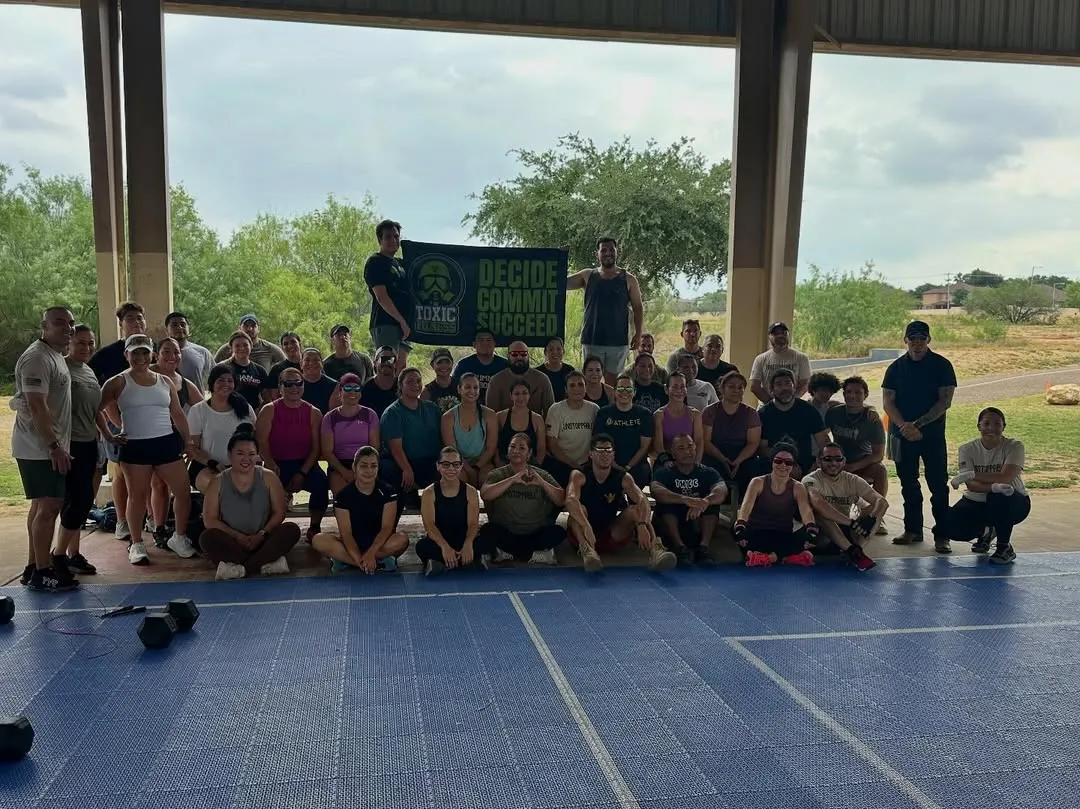 Toxic Fitness members gathered under the Decide · Commit · Succeed banner