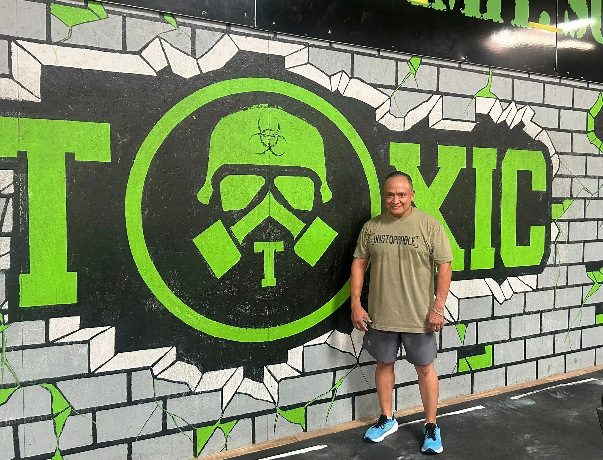 An athlete in front of the Toxic Fitness gas-mask mural