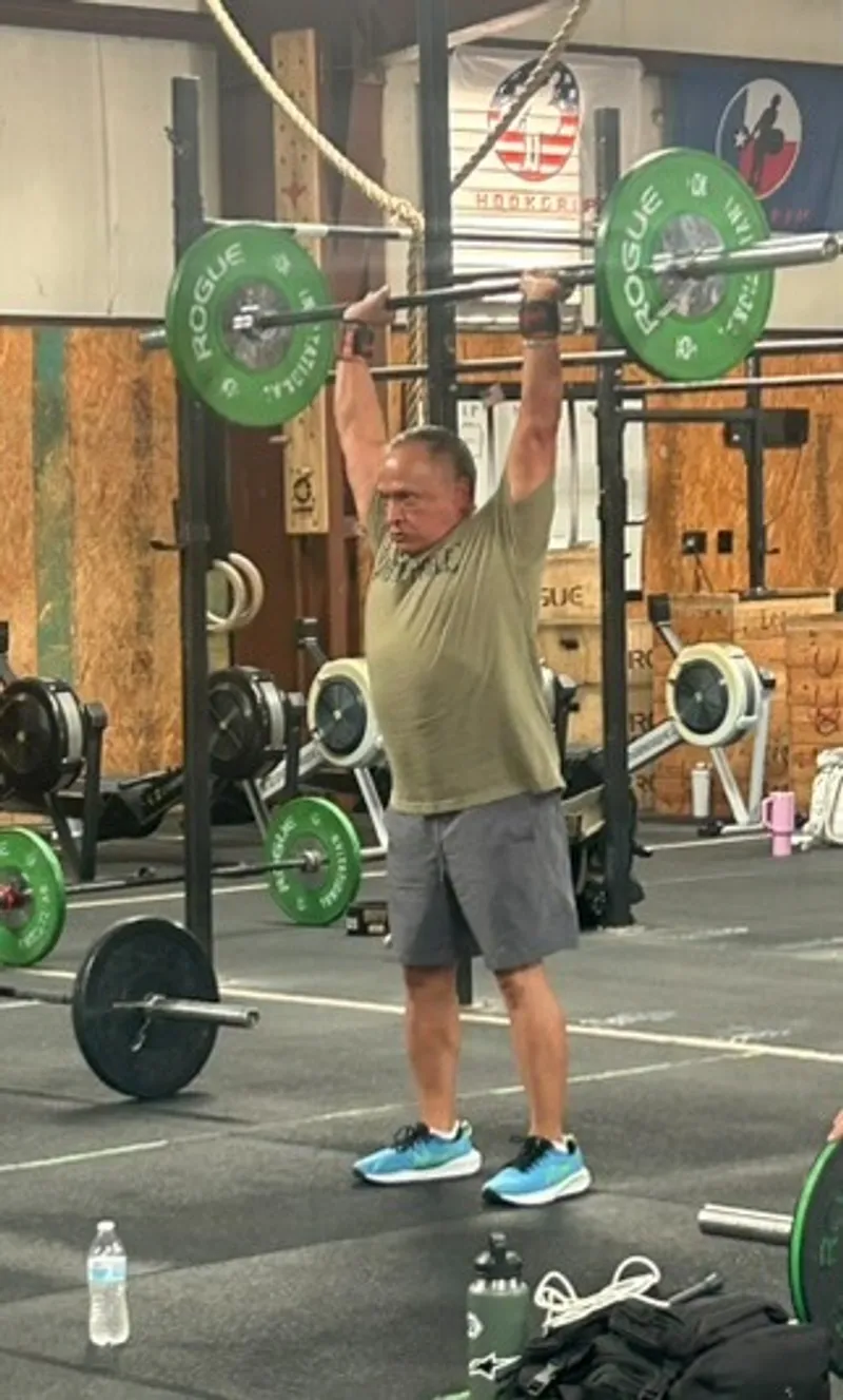 Overhead press on the platform surrounded by green bumper plates