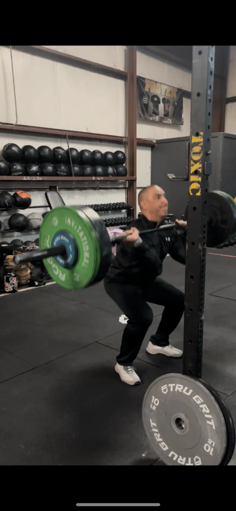 Front squat under a loaded barbell on the Toxic Fitness training floor